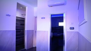 Un pasillo con diseño moderno, que incluye un equipo de aire acondicionado de pared y una puerta que da a un baño.