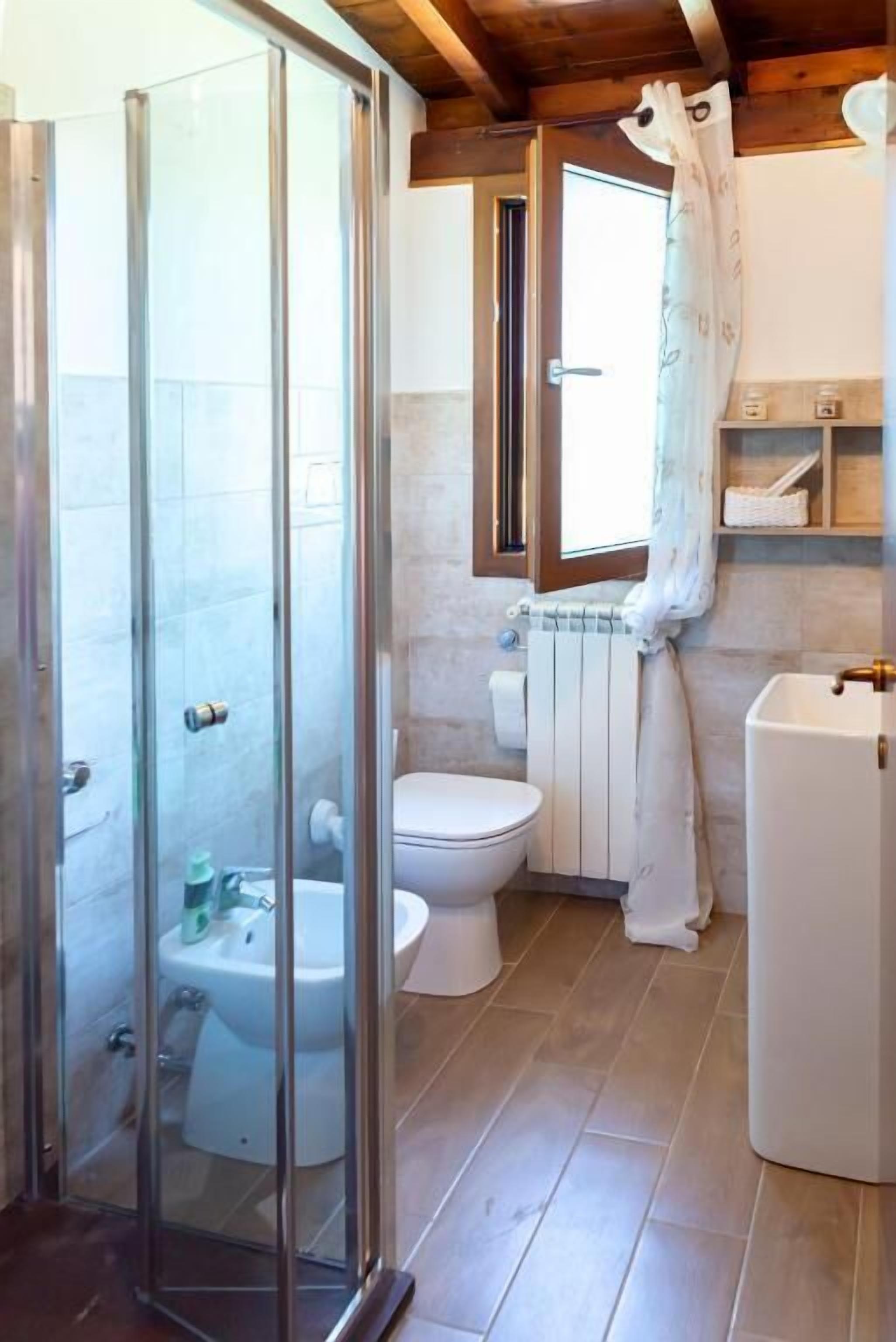 Une salle de bain avec une douche à parois de verre, des toilettes, un bidet et un radiateur.