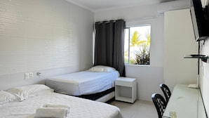 Een hotelkamer met een bed, een bureau, een stoel, een televisie en een raam met gordijnen.
