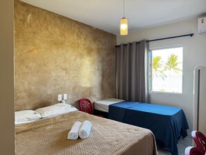 A hotel room with a bed, a desk, a chair, and a window with curtains.