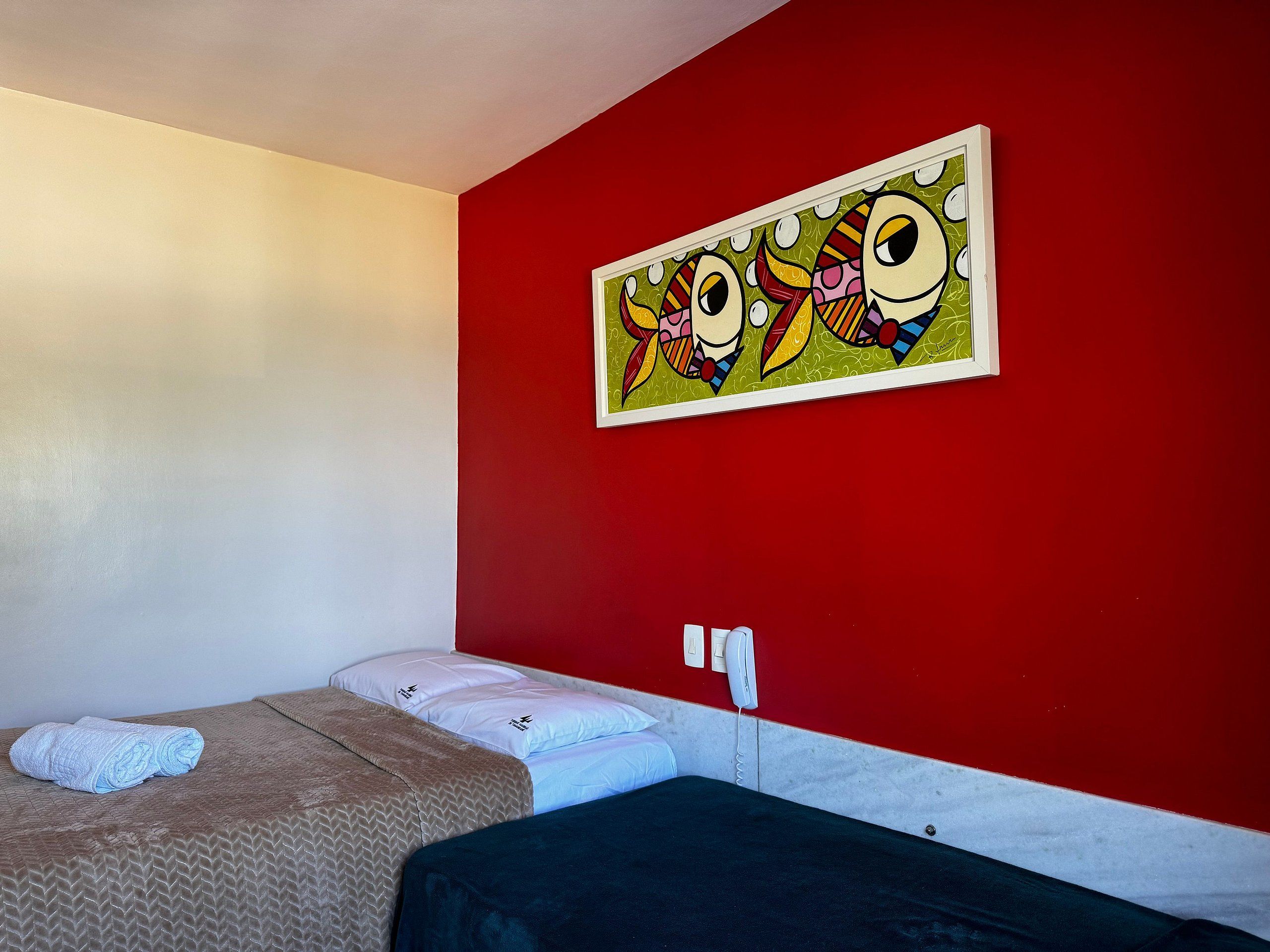 Quarto de hotel com cama, telefone e um quadro na parede.