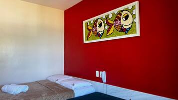 Quarto de hotel com cama, telefone e um quadro na parede.