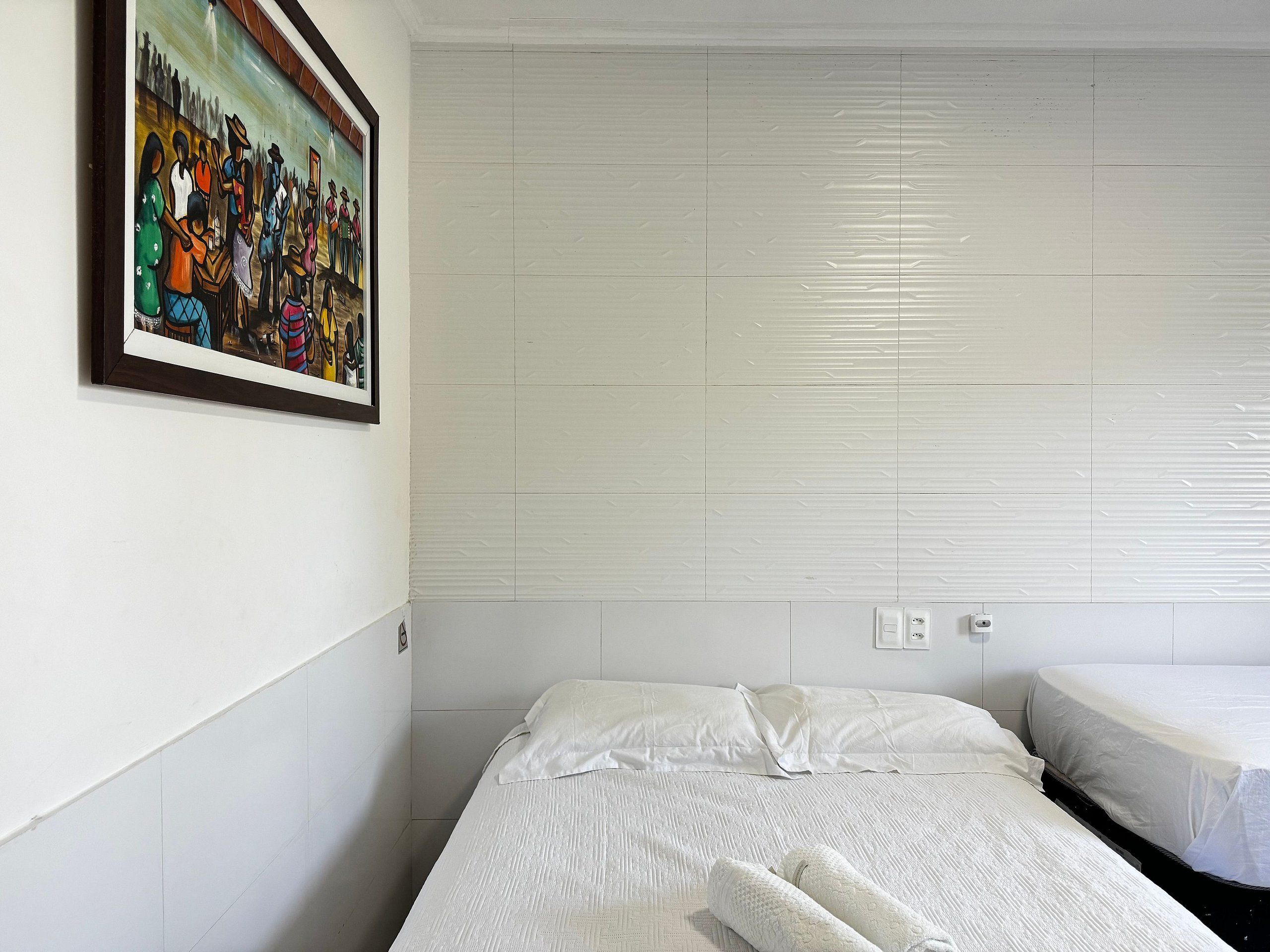 A hotel room with a bed, a small bedside table, and a wall-mounted painting.