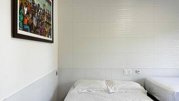 A hotel room with a bed, a small bedside table, and a wall-mounted painting.
