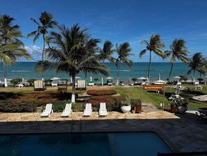 A poolside area with lounge chairs, a sign for 'Apart Hotel Marinas', and a view of the ocean.