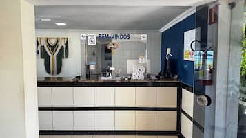 Un espace d’accueil avec un comptoir, une pancarte indiquant « BIENVENUE » et un extincteur fixé au mur.