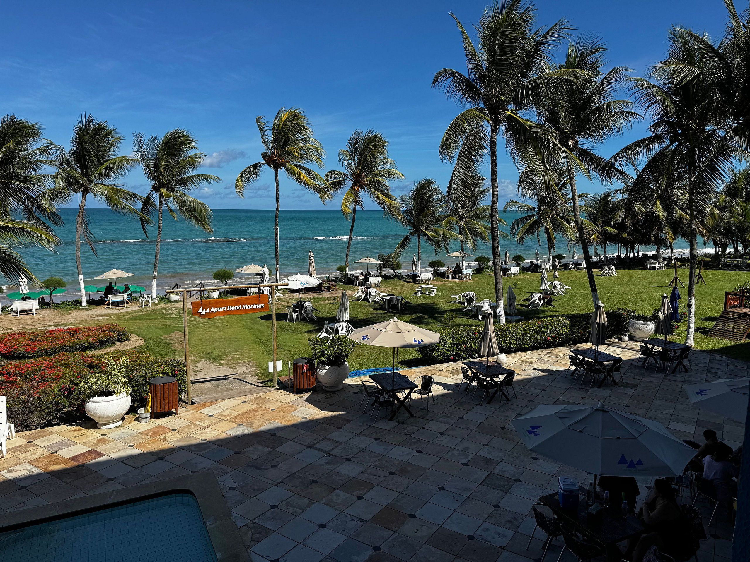 A resort with a pool, outdoor seating, and a view of the ocean.