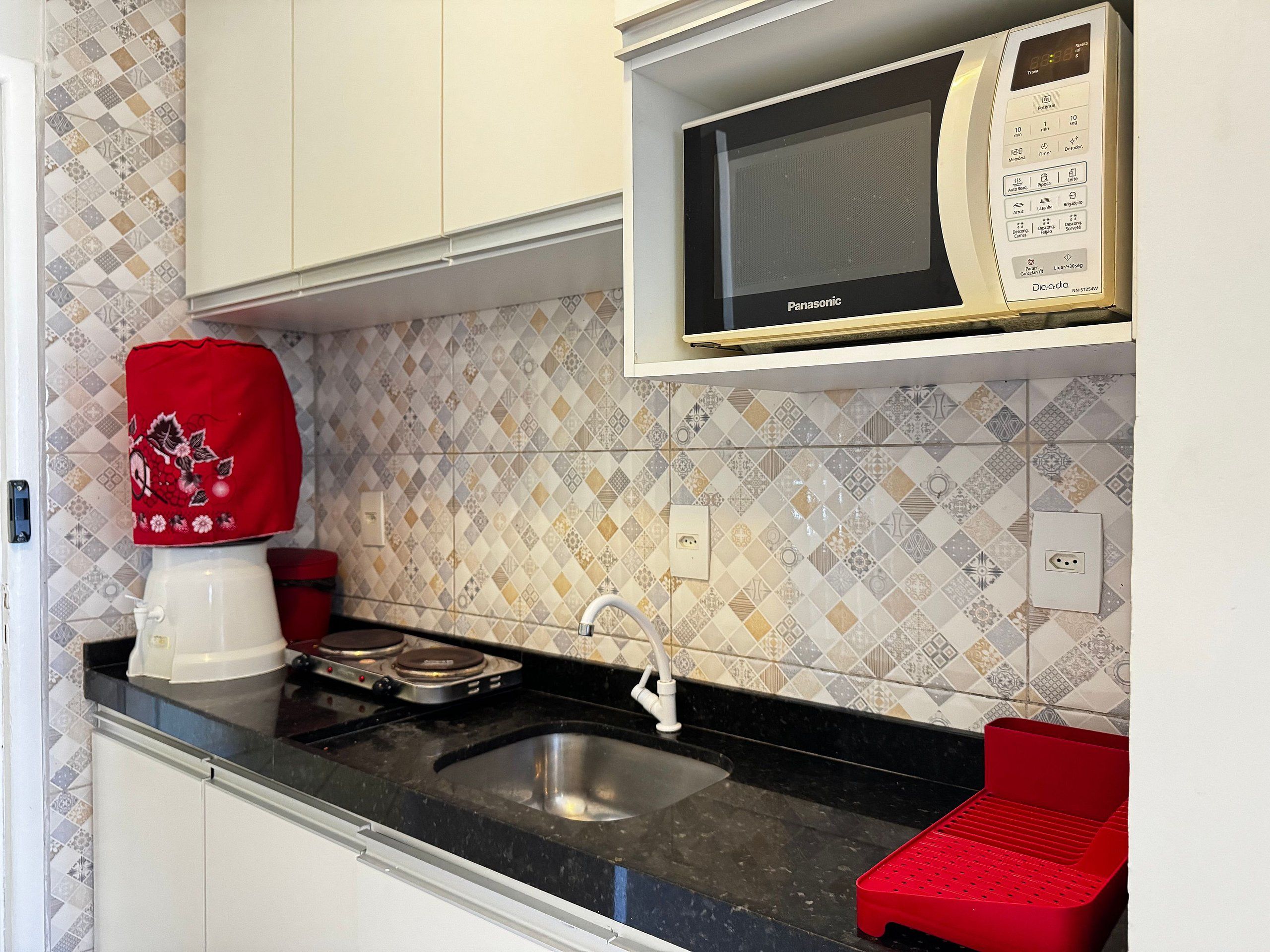 A kitchen with a microwave, a coffee maker, and a red tray.