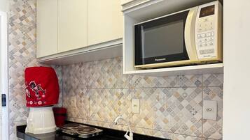 A kitchen with a microwave, a coffee maker, and a red tray.