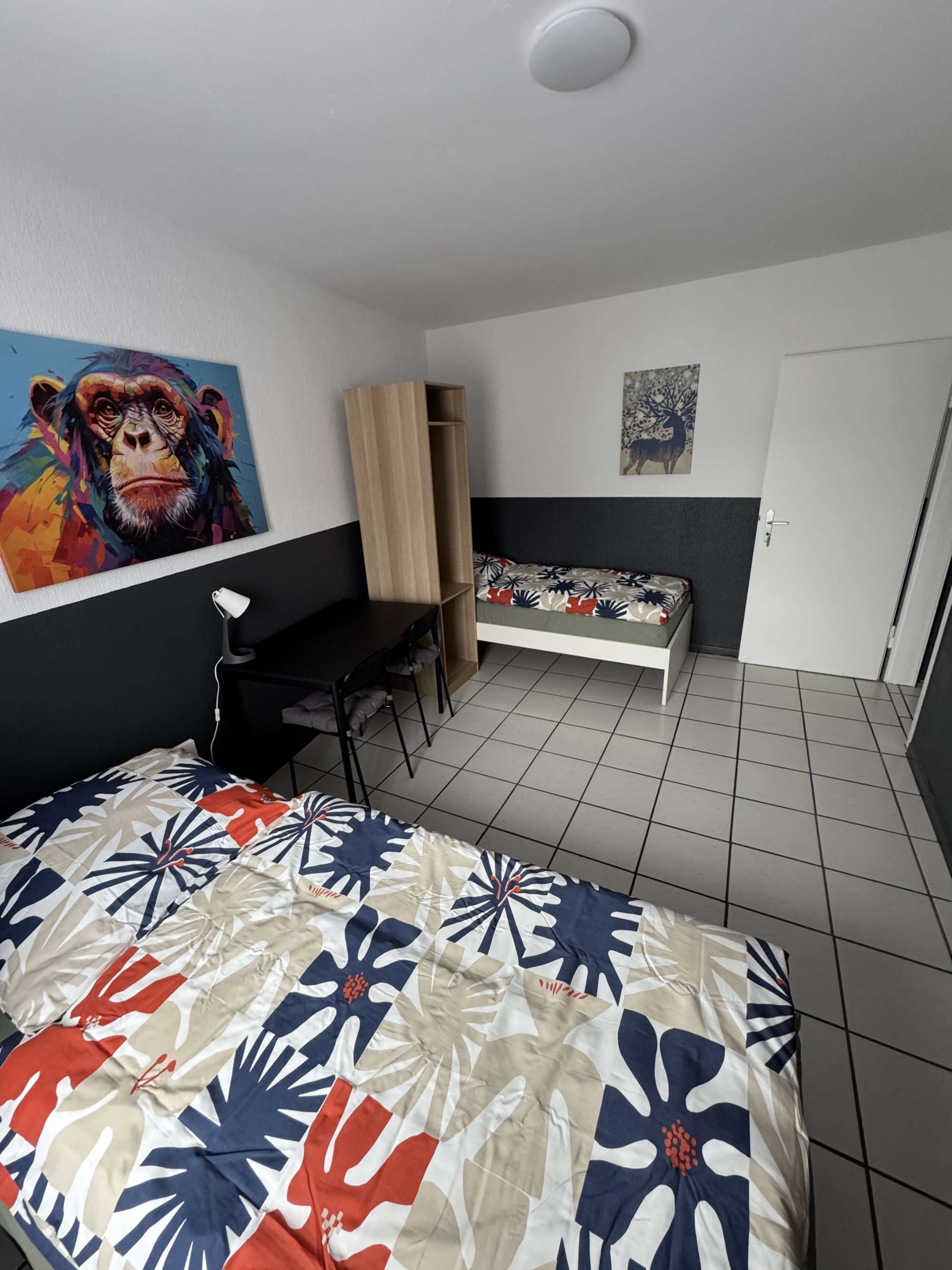 Ein Zimmer mit einem Bett, einem Schreibtisch, einem Stuhl und einer Wand mit einem Gemälde.