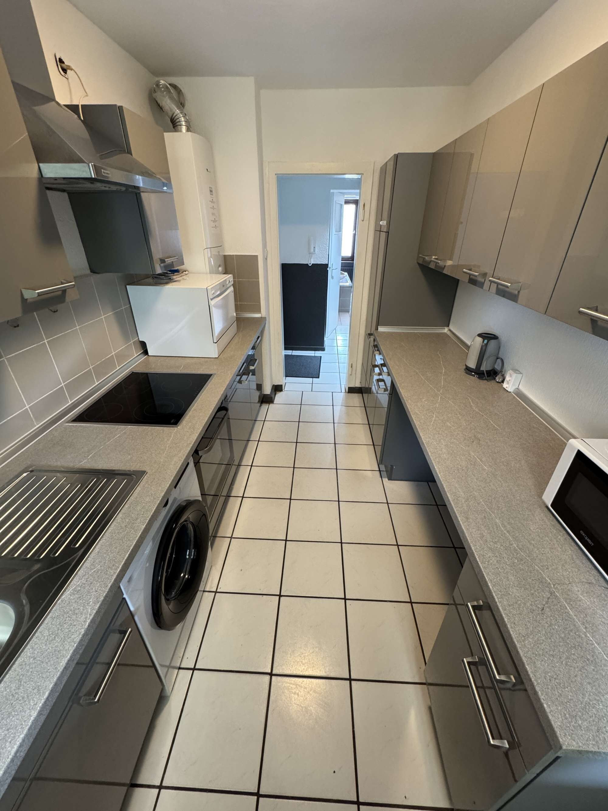 A modern kitchen with a built-in washer, a stove, and a microwave.