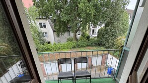 Ein Balkon mit zwei Stühlen, einem grünen Kunstrasen und Blick auf die Nachbarschaft.