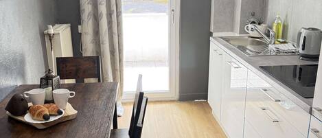 A modern kitchen with a dining table, chairs, and a view through the door.