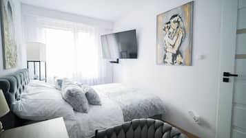 Een moderne slaapkamer met een bed, een flatscreen televisie, een schilderij en een lamp.