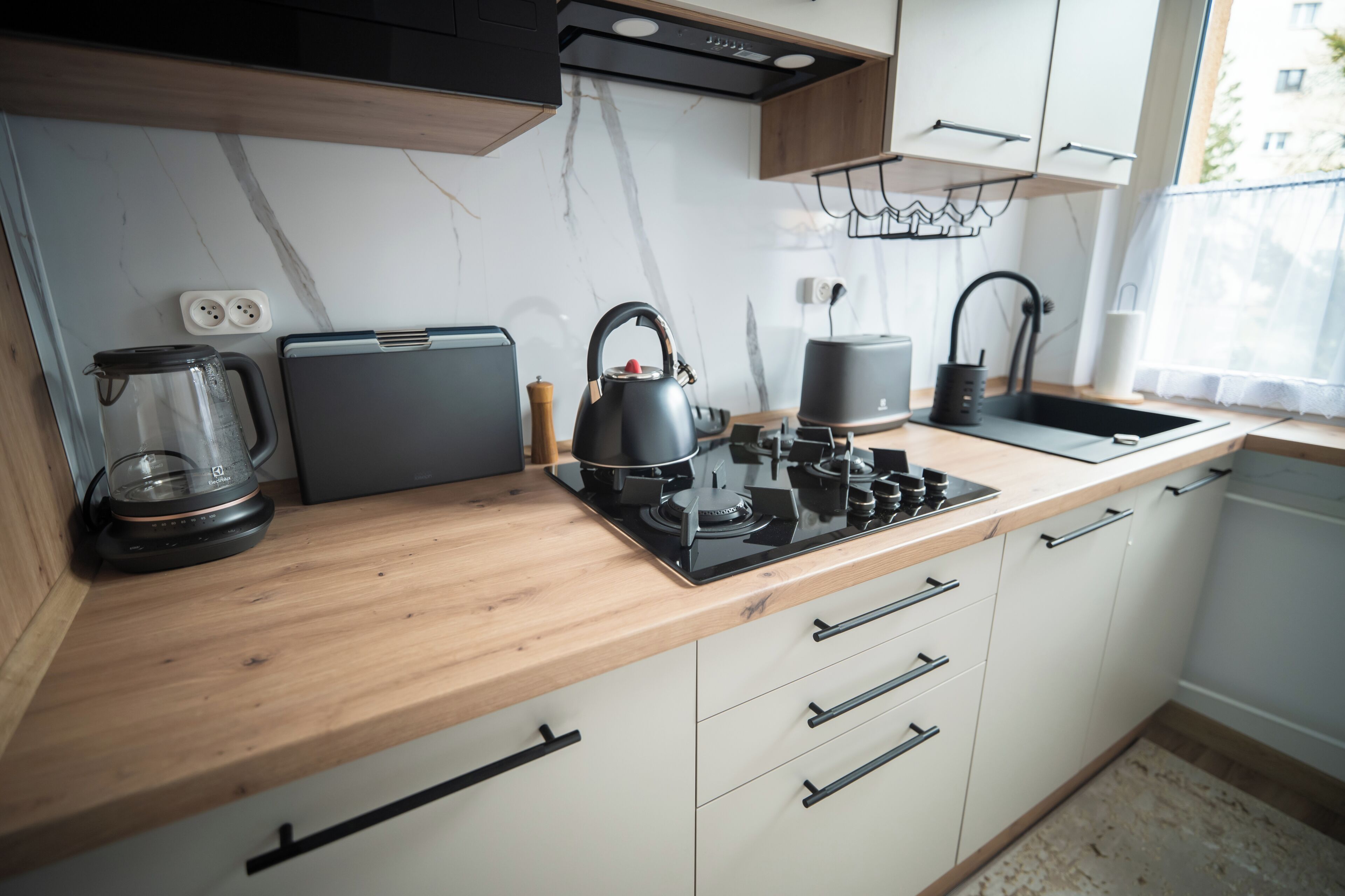 Une cuisine moderne dotée d’un plan de travail en bois, d’une bouilloire, d’une machine à café et d’une cuisinière.