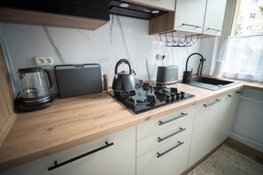 Una cocina moderna con encimera de madera, un hervidor, una cafetera y una estufa.