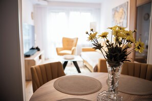 A dining area with a round table, chairs, and a vase with yellow flowers.
