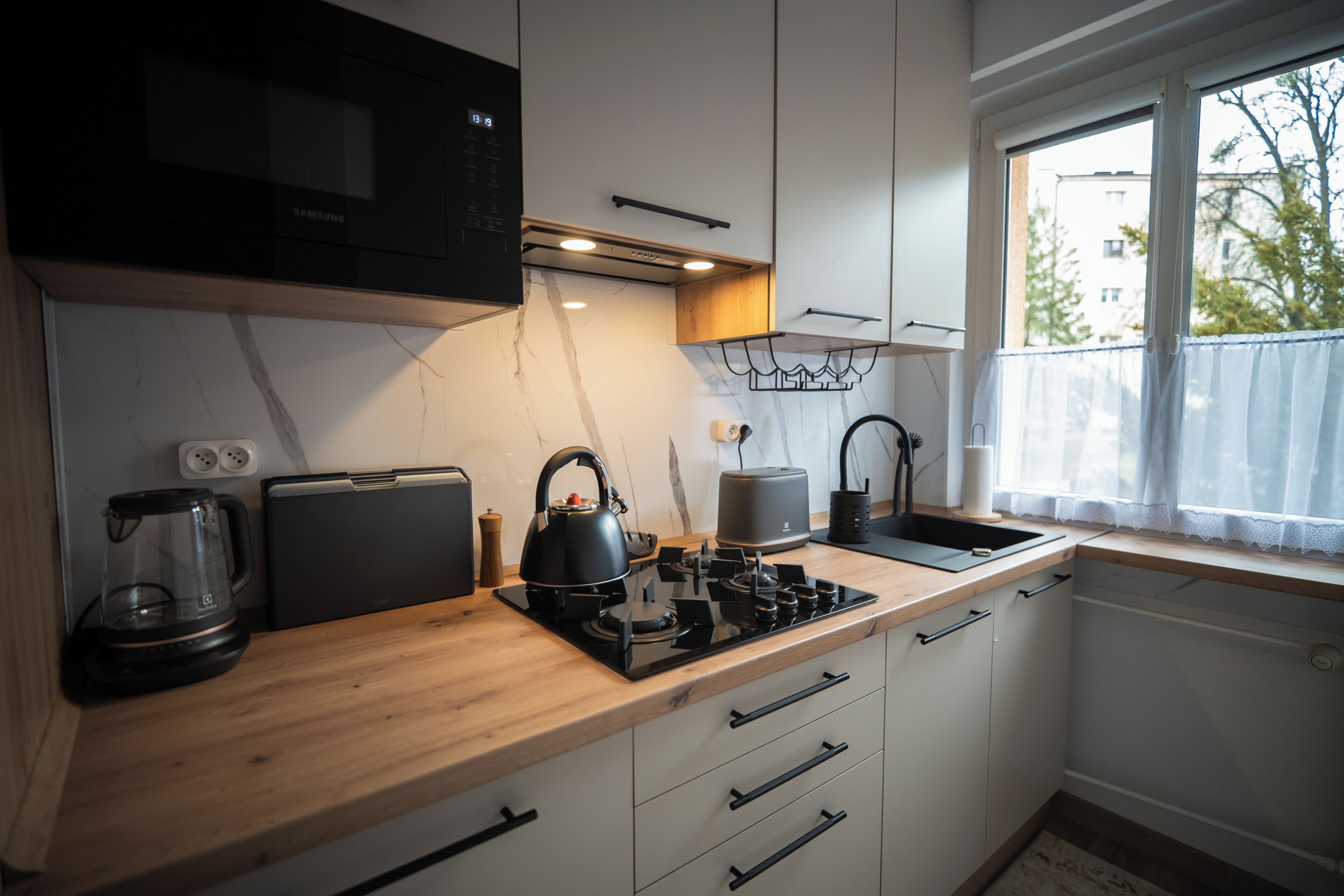 Una cocina moderna con microondas, hervidor, tostadora y ventana con vistas al exterior.