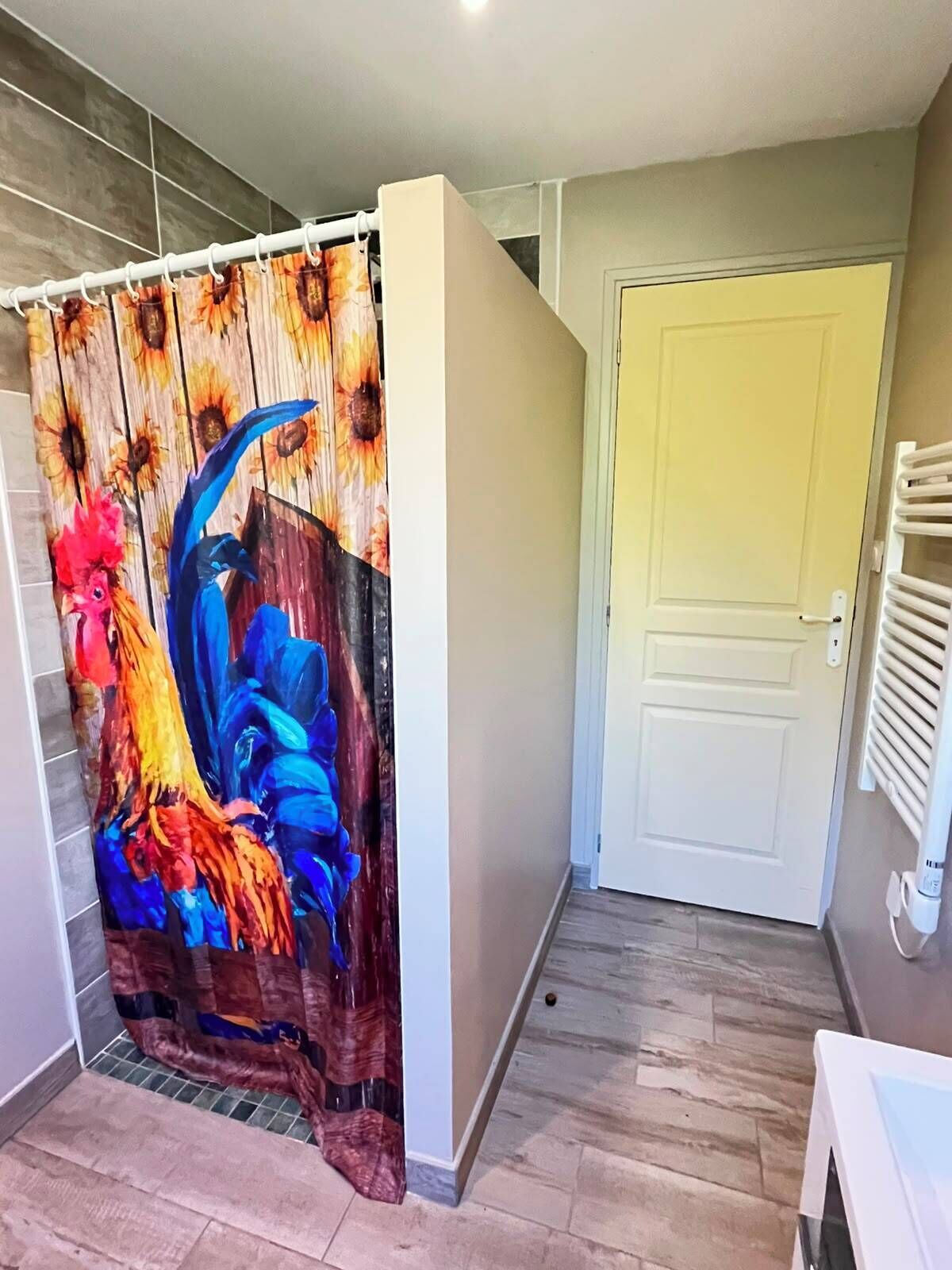 A room with a shower curtain featuring a rooster design, a white door, and a radiator.