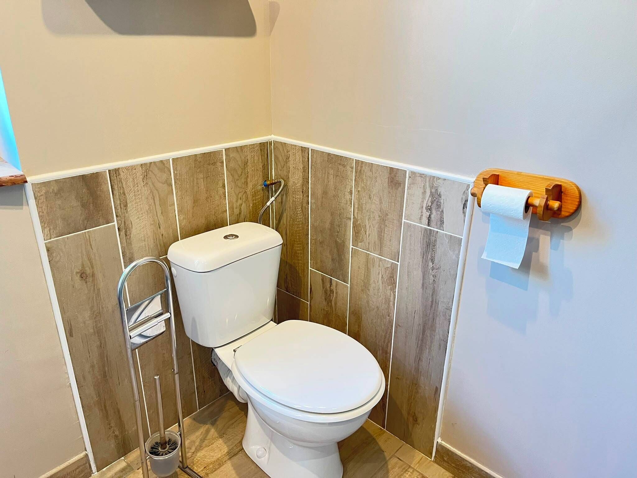 Une petite salle de bain comprenant des toilettes, une douche et un porte-rouleau de papier toilette.