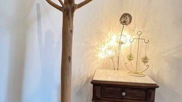 Un perchero de madera con ramas y una mesita con una lámpara.