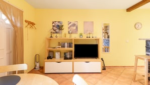 Una sala de estar con televisor, estanterías y una zona de comedor.