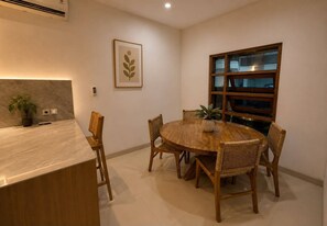 A dining area with a round wooden table and wicker chairs, a potted plant, and a framed artwork on the wall. - Dala Villa Ubud (Gianyar)