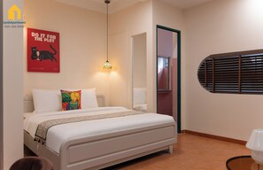 Una camera da letto con un letto, un quadro, una lampada a sospensione, una porta e una finestra con persiane.