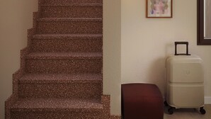A staircase with a textured finish, a wall-mounted artwork, and a wheeled suitcase. - Numa Florence Fiesolana (Firenze)