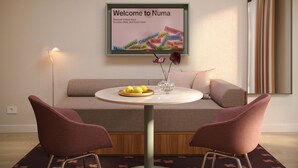 A modern living room with a round table, two chairs, a sofa, a hanging light fixture, and a welcome sign. - Numa Florence Fiesolana (Firenze)