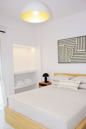 A modern bedroom with a bed, bedside table, lamp, and a geometric wall art piece. - Luxury City Apartment, 3 bedrooms 3 bathrooms, Chania Center (Chania)