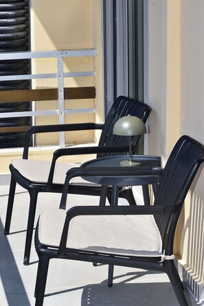 A balcony with a table and two chairs, a lamp, and a radiator. - Luxury City Apartment, 3 bedrooms 3 bathrooms, Chania Center (Chania)