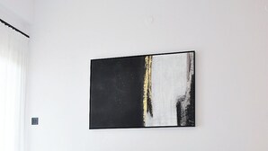 Uma sala de estar moderna com um sofá seccional, uma mesa de centro redonda preta e uma grande pintura abstrata na parede.