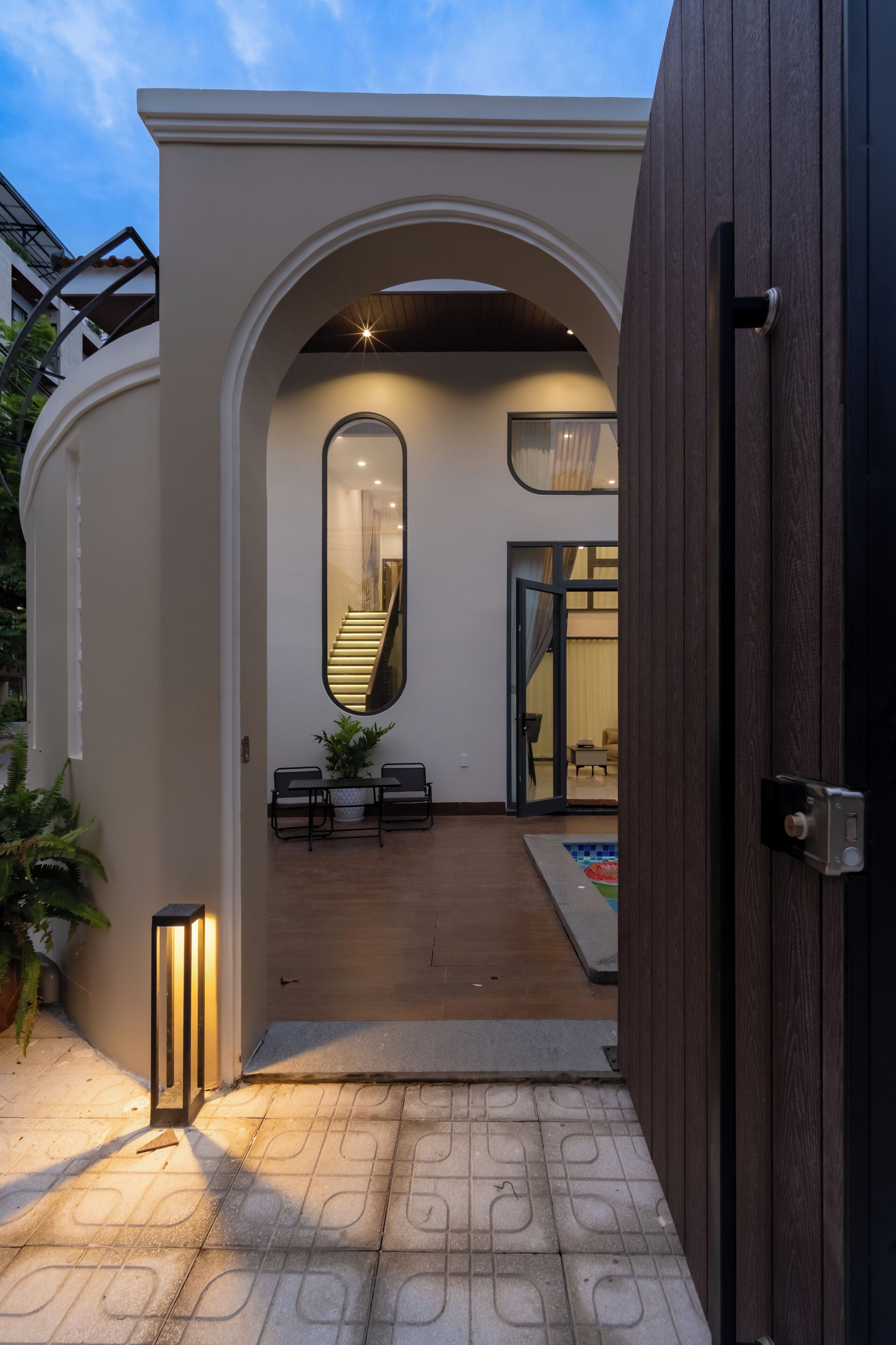 Una casa moderna con un porche cubierto, una escalera y un espejo grande.