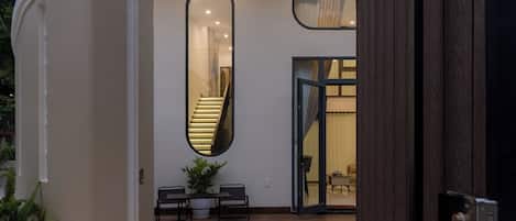 A modern house with a covered patio, a staircase, and a large mirror.