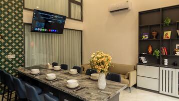 A modern kitchen with a central island, bar stools, a flat-screen TV, and a ceiling fan.