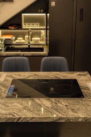 A kitchen with a built-in induction cooktop, a sink, and a countertop. - H VILLA  (Da Nang)