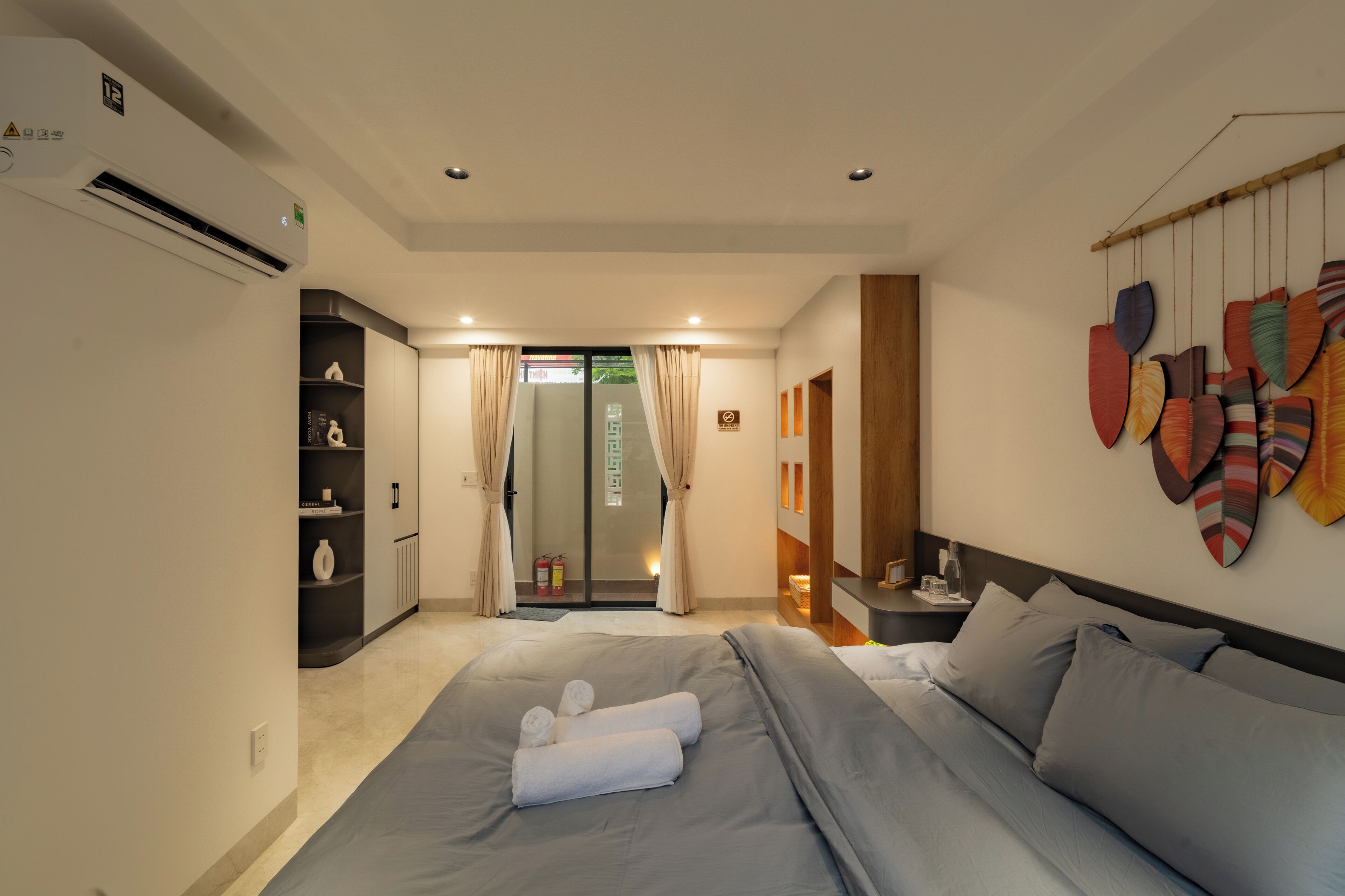 Quarto de hotel com cama, guarda-roupa, banheiro e parede decorada.