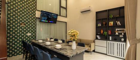 A modern kitchen with a central island, bar stools, a flat-screen TV, and a built-in bookshelf.