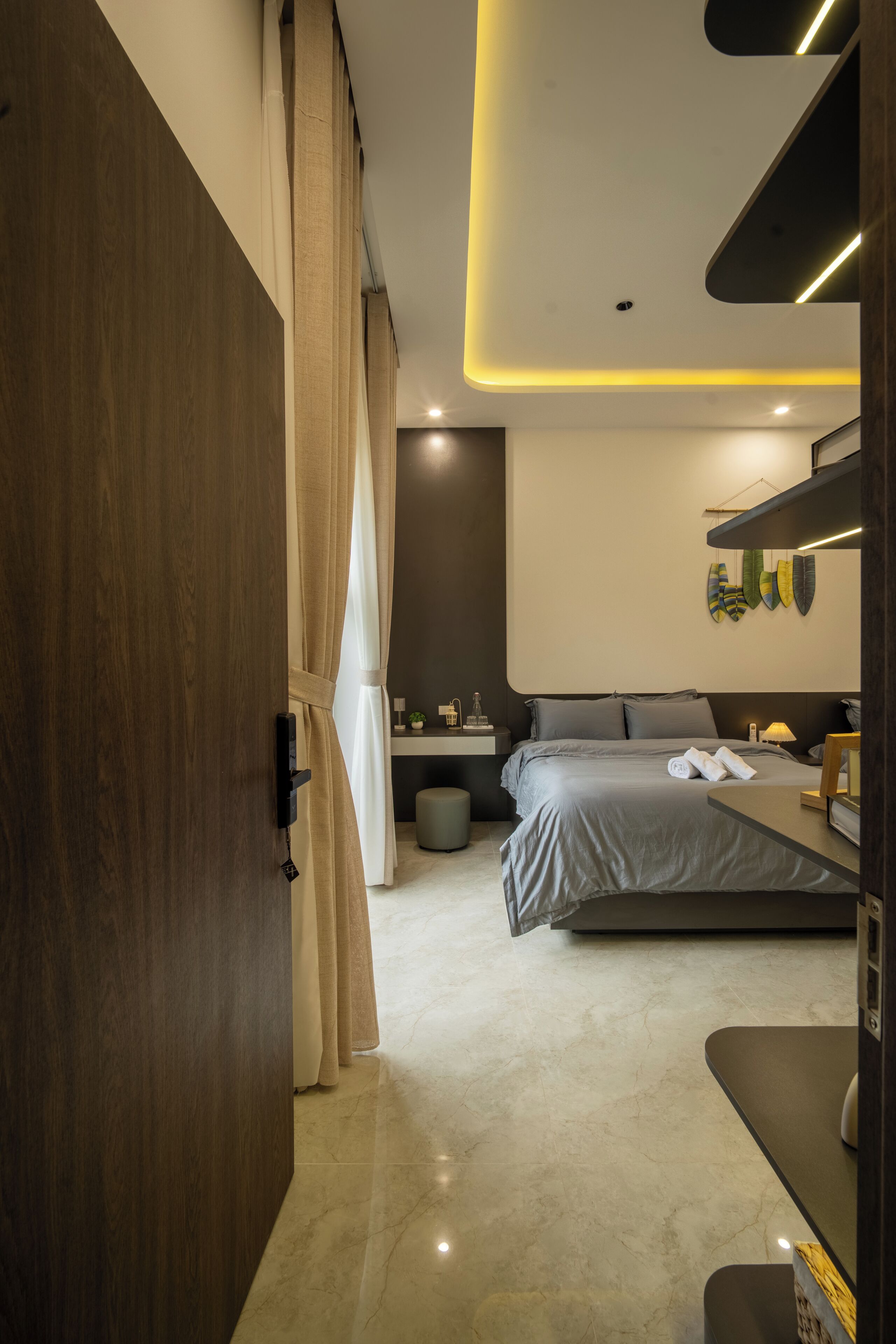 A modern bedroom with a bed, bedside table, and a bathroom in the background.