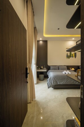 Un dormitorio moderno con cama, mesita de noche y un baño al fondo.