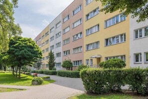 A multi-story residential building with a paved pathway and greenery. - Spacious Air-Conditioned Apartment | 2 Bedrooms | Workspace (Warszawa)
