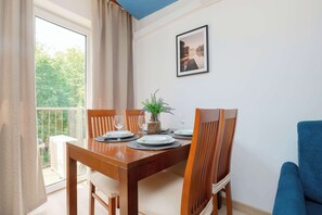 Een eethoek met een houten tafel, stoelen en een vaas met bloemen.
