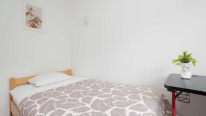 A bedroom with a bed, a bedside table with a vase, and a wall-mounted light. - Spacious Air-Conditioned Apartment | 2 Bedrooms | Workspace (Warszawa)