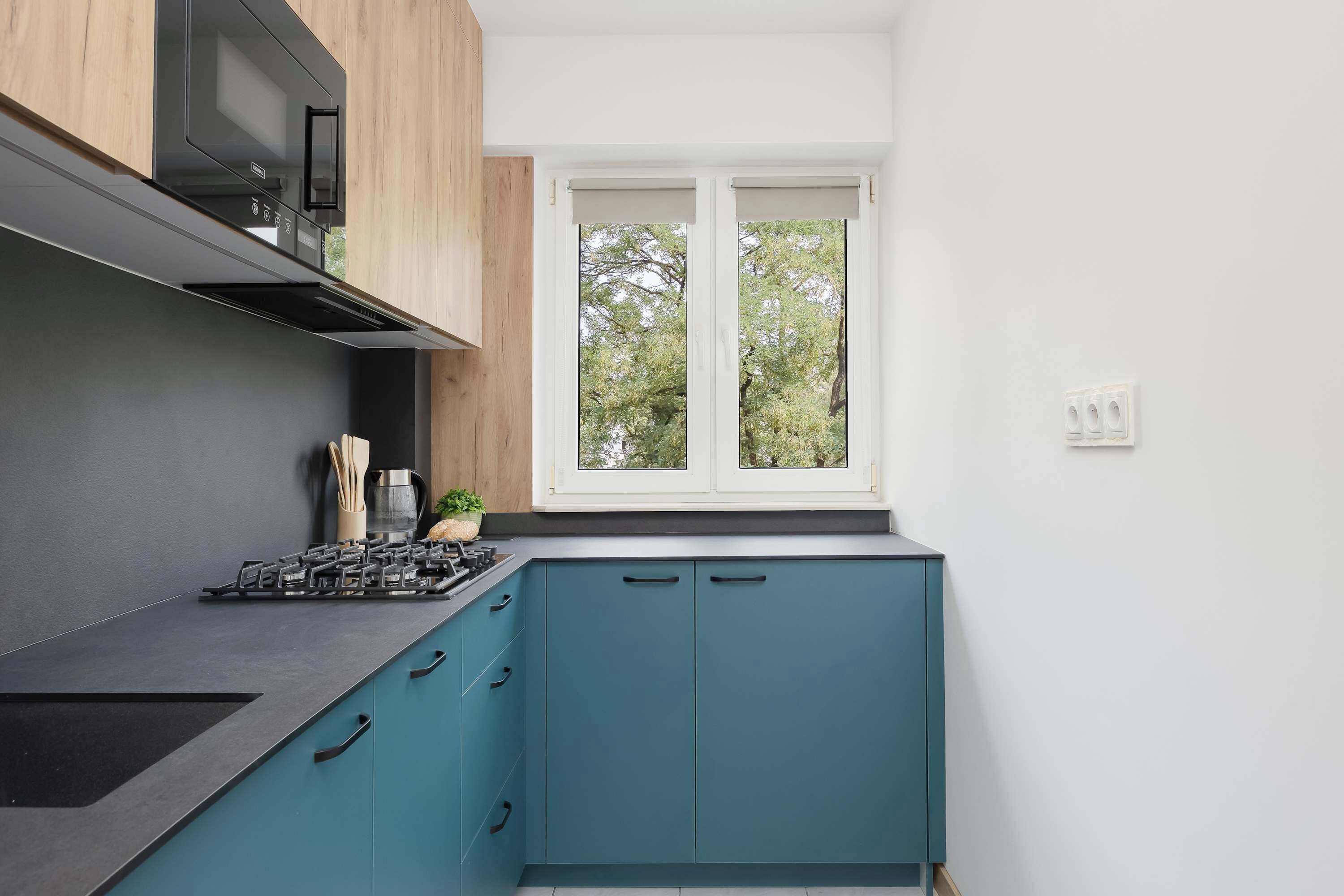 Una cocina moderna con estufa a gas, armarios y una ventana con vistas a árboles.