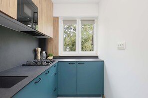 Eine moderne Küche mit einem Gaskochfeld, Schränken und einem Fenster mit Blick auf Bäume.