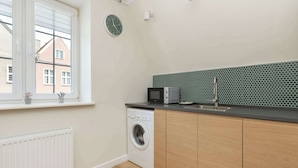 A compact kitchen with a washing machine, a microwave, and a sink. - Cosy Studio in the Downtown in Gdansk by Noclegi Renters (Gdańsk)