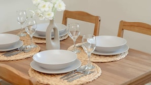A dining table set with plates, cutlery, and glasses, accompanied by a vase of white flowers. - Cosy Studio in the Downtown in Gdansk by Noclegi Renters (Gdańsk)