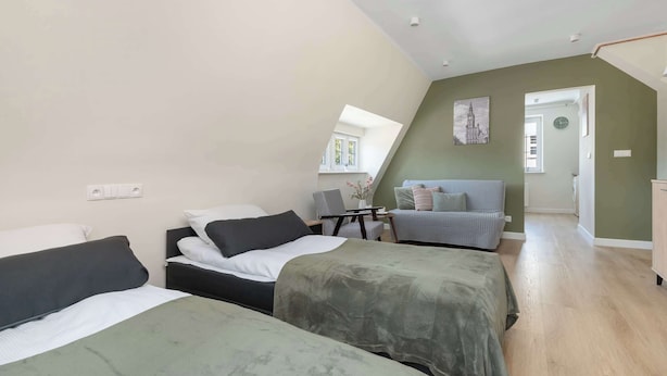 A loft-style bedroom with two beds, a sofa, and a dining table. - Cosy Studio in the Downtown in Gdansk by Noclegi Renters (Gdańsk)