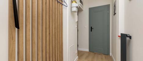 A hallway with a wooden panel wall, a radiator, and a door at the end.
